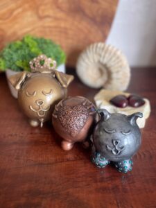 three urns for pets. one gold dog, one silver cat, and one urn with a heart